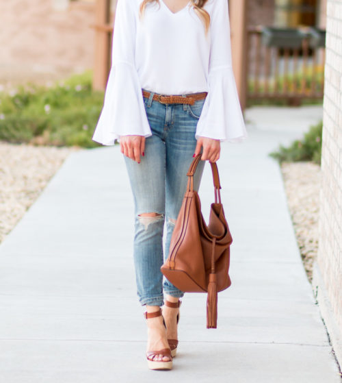 Kristyn Ann wearing a white Wayf bell sleeve blouse with Current Elliott the Stiletto Jeans in Ticker Destroy and a Rebecca Minkoff Isobel Hobo Bag.