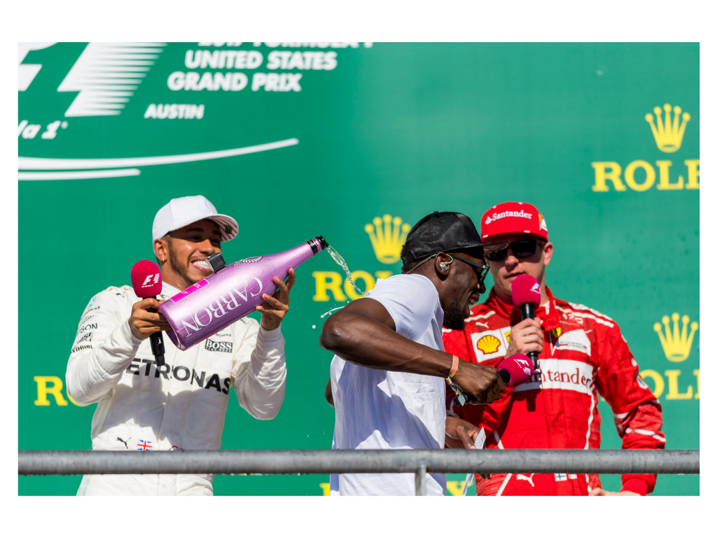 Hamilton, Sunday’s fastest man on four wheels, pours champagne on Olympic champion Usain Bolt, one of the fastest men on two feet.