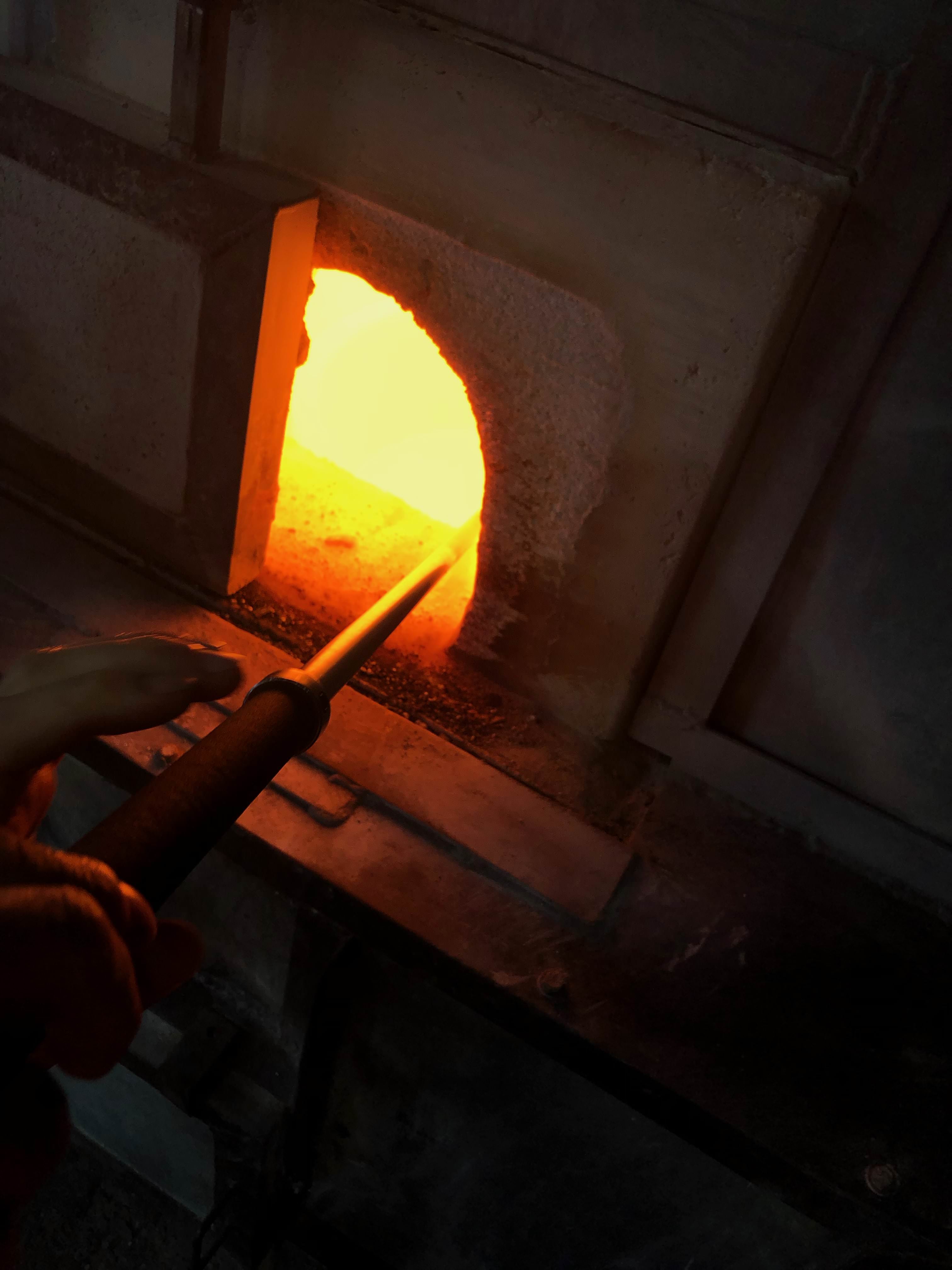 Retrieving molten glass from a glowing hot oven at Flame Run